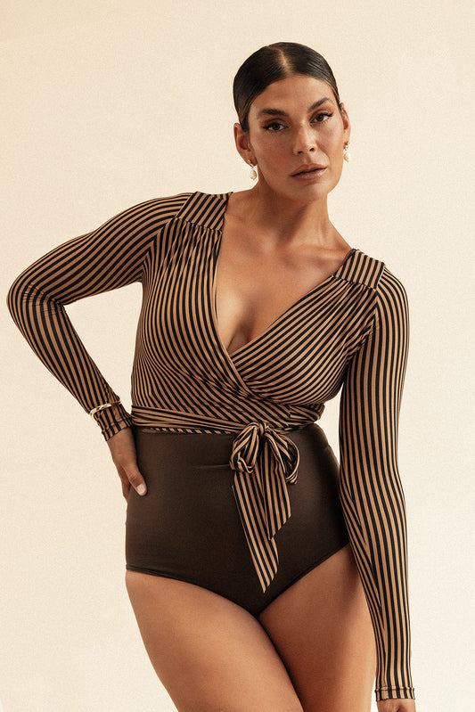Woman wearing a long sleeve swim wrap top with a coffee and black striped pattern. The top is tied at the centre of the waist with a bow.