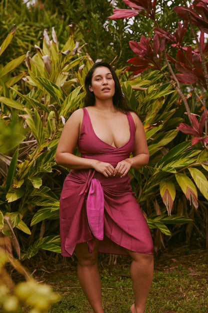 Woman poses in the garden wearing a pink sarong