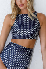 Woman poses in high waisted geometric bikini set.